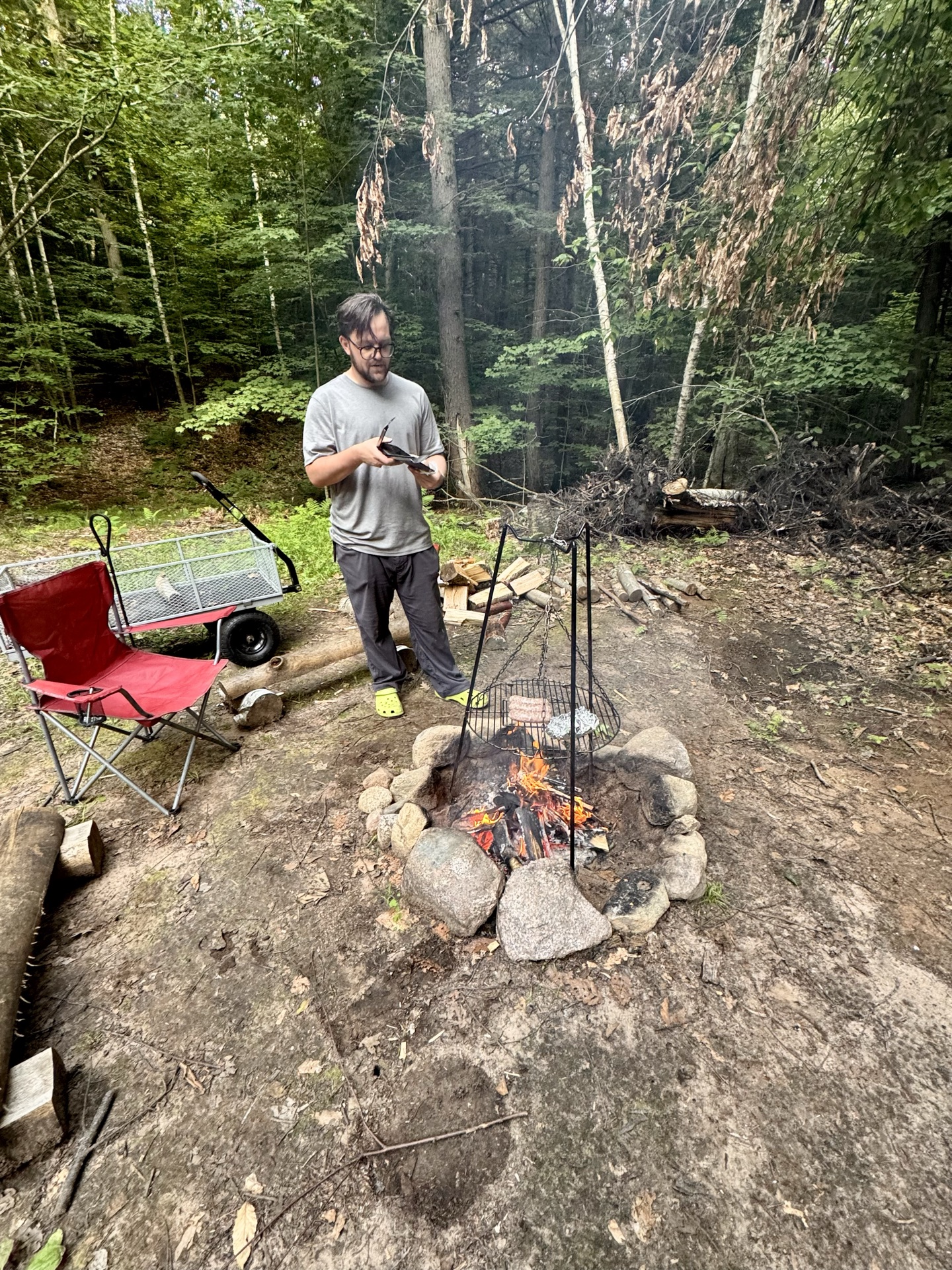 Brats grilling over campfire coals on the swing-arm grate